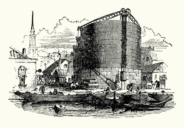 Print. Boats line up at a dock in front of a round, silo-like building. More structures as well as people and horses surround it, and a church steeple rises in the distance of this black and white engraving.